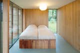 Light breaks through the bedroom's north wall through a vertical window that cuts from the floor up past the second floor mezzanine to the roof's ridgeline. The bed is custom.