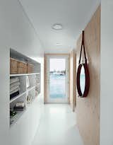 Doors, Swing Door Type, and Interior The narrow entrance hall faces another door, which opens seaward. Built-in cabinets serve as both storage and display. The porthole mirror is by Jacques Adnet.  Search “mirrorsconsole table mirror” from Each Day at This Floating Home Begins With a Swim, Just Two Feet From Bed
