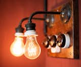 Old-fashioned filament lightbulb fixtures hang on the wall. Photo by: Martin Kaufmann