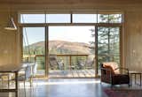 Supported by steel strips, the balcony extends outwards to meet the valley below. Fully-glazed sliding doors and a clerestory window provide a view.
