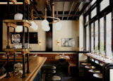 White brick walls and high glossed ceilings clad the interior. At the bar, open wood-and-metal stacked shelving stores various restaurant wares, such as glasses, matchbox jar, and mini condiment containers.