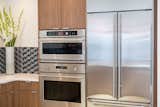 The appliances in the home include a 30" Advantium Speedcook Oven and Single Wall Oven, as well as a 36" induction cooktop with a Glass Canopy Hood above.