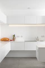 The stark white minimalist kitchen features quartz countertops, a Gessi Oxygene tap, a 1810 Company Zenuno sink, and energy-efficient Bosch appliances.