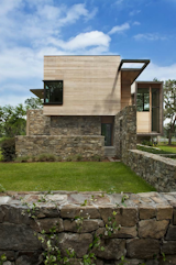 Choate built the house with weathered fieldstone on the lower level and clear-grained cedar above. A copper horizontal datum line extends into what Choate calls a "shadow-caster"—a skylight-like void designed to mark time and cast a shadow on the building as the sun moves across the site.