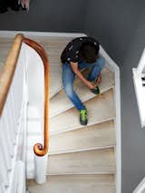 Staircase, Wood Railing, and Wood Tread Charrier’s son, Fabian Fonnesbæk Charrier, 14, pauses on a staircase of white oil-finished pine floorboards.  Photo 3 of 12 in A Cramped Attic Became a Sunny Dining Room in this Renovation of a Copenhagen Tudor