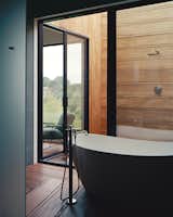 The master suite’s bathroom unfolds from a glass-walled bathing room, outfitted with a Signature Hardware tub and Lefroy Brooks fixtures, to an open-air shower.