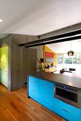 A dark concrete counter and blue laminate cabinets surround the Jenn-Air microwave drawer in architect Janet Bloomberg’s kitchen. The pendant hanging above the table is a Tejido Round Suspension from Artemide.