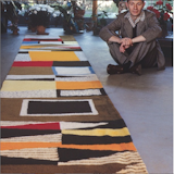 Alexander Girard sitting beside a custom rug for the Rieveschl home he designed in Grosse Point, Michigan, 1951.