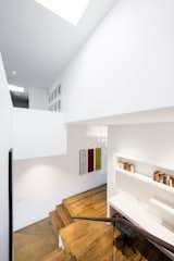 This double-height stairwell, just adjacent to the kitchen, marks the transition from the historic building to the new renovation. A skylight pulls sunlight from above into the home office below.