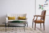 In the shop, a Luc Bernard painting hangs near a settee in oatmeal linen, a marble-topped coffee table, and a vintage Moroccan wool rug.