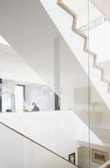 Staircase and Glass Railing Large windows by Alumilex and an operable Velux skylight—with built-in rain sensor to automatically close it in case of unexpected showers—flood the home with light. A glass wall surrounding the staircase reflects a chalk mural by artist Tyson Bodnarchuk.  Photo 5 of 11 in An Architectural Mishmash in Montreal Becomes a Long-Term Family Home