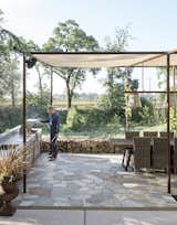 Outdoor, Large Patio, Porch, Deck, and Stone Patio, Porch, Deck An outdoor dining area is shaded by a mesh canopy suspended by old drilling pipes.  Photo 7 of 14 in A Homeowner Uses Smart Technology to Manage His Napa Property from Anywhere