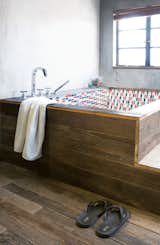 Bath Room and Soaking Tub All of the floorboards in the house, as well as the wooden panels encasing the bathtub in the main bathroom, are made of antique door frames.  Photo 10 of 11 in Modern Lilong House Renovation in Shanghai