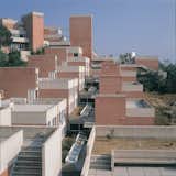 “Collegi” buildings, Giancarlo De Carlo, 1962–1982, Urbino, Italy.

Italian architect Giancarlo De Carlo, a core member of the radical architecture collective Team Ten, achieved international acclaim when he created the five “Collegi” buildings (Colle, Tridente, Serpentine, Aquilone, and Vela) at the Università degli Studi in the rolling landscape near the medieval city of Urbino. He championed the philosophy that modernist architecture should support social change, and used this principle to design over 62,000 square feet of buildings that function as “an organism in the form of a city” by repeating simple structural elements that respond subtly to the surrounding hillside topography. A close relationship to nature is reinforced by a series of open public spaces that are connected through a unique system of flowing internal “streets.” Unfortunately, the palette of modern materials selected by the architect have not performed well over time and current safety regulations and campus usage patterns have led to the under-utilization of many of the open spaces at the heart of De Carlo’s design. A Getty grant will support a comprehensive conservation plan for the structures that will address material deterioration and adaptation that is sensitive to contemporary use but also respects the architect’s original vision. Grant support: $195,000