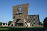 Saint John’s Abbey and University Church, Marcel Breuer, 1961, Collegeville, Minnesota.
In the 1950s, the Benedictine monks of Saint John’s Abbey made the daring choice of Bauhaus architect Marcel Breuer for the design of a new church for its growing monastic community and student community located on the joint campuses of the Minnesota’s College of Saint Benedict and Saint John’s University. In response to the clergy’s call for a church that would be “an architectural monument to the service of God,” Breuer deployed a striking combination of concrete and stained glass to create a masterful juxtaposition of levity and mass. The church’s entrance is framed by a weighty bell tower, a dramatic contrast to its perforated, honeycomb façade. Encased stained glass, as well as large interior skylights and windows spanning the building’s sides, flood the church interior with light and balance the massive concrete framing buttresses. Today the structures are the architectural centerpiece of more than a dozen other structures by Breuer on this multi-use complex, forming the largest collection anywhere of a single modernist architect’s work. A Getty grant will support a conservation management plan to guide a long-term preservation strategy for these buildings. Grant support: $150,000