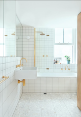The bathroom was creatively composed using inexpensive Quarella Calacatta floor tiles, a Villery & Boch wall-mounted sink, and a Reece Sabine bath. Brass electroplated fixtures and FLOS Mini Glo Ball wall lights add a touch of sass to an otherwise understated space.