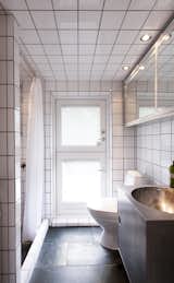 In the bathroom, plain white tiles line the walls and ceiling. The floors are natural stone and the fixtures are by VOLA. Lassen built the sink himself.