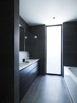 The home's mostly neutral palette continues in the black-and-white bathroom. The vanity top is made of Carrara marble and the Kaldewei bath is from Reece.