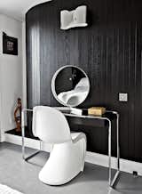 Near the room’s curving wall, a Verner Panton chair joins a K2 B console table by Tecta, topped by a vintage mirror by Robert Welch. The wall light is from Flos. "If I had more space, I’d just fill it with more stuff," says Pearce. The black-and-white palette echoes the home's exterior.