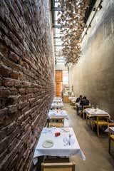 The design team preserved one of the original brick walls, which dates to 1870, but created a modern contrast by covering the other wall in smooth concrete. A sculptural piece by Santiago Lena hangs from the ceiling.