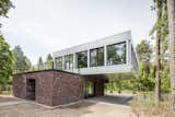 Outdoor The lower level is covered in traditional red brick, while the upper level consists of coil-coated aluminium sheet with large glass panes.  Search “cascade coil drapery” from Striking Cantilevered Home Pairs Brick and Aluminum