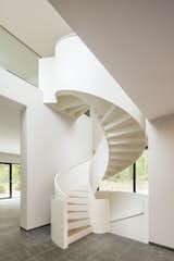 A sculptural white steel spiral staircase with wooden treads connects the two levels.