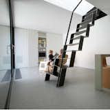 Dekleva Gregorič Architects turned a former utility building into a stylish, self-sufficient home with a downstairs living space and bathroom linked to two upstairs bedrooms by a sculptural, custom-designed black iron staircase. The central, welded-iron staircase is the house’s most striking contemporary feature. Beyond it, more large sliding doors conceal extra storage and the home entertainment system.