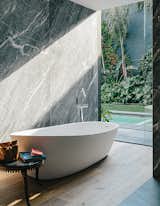 An Almond bathtub by Porcelanosa is accented by a tub filler from Hansgrohe.