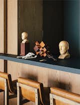 In the dining room, antique wooden busts and a machiche cross designed by Farca are arranged on a resin countertop by Monica Calderon. The bar conceals a service area with an espresso machine.
