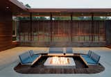 Architect Matthew Hufft of Hufft Projects applied a ring of ipe around the perimeter of this fire pit on the patio of the Curved House in Missouri.The outdoor area, which was designed in collaboration with Weston, Missouri-based landscape architecture firm 40North, features removable powder-coated aluminum benches upholstered in Sunbrella fabric.