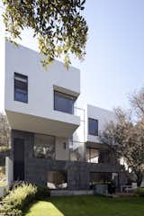 The home's materials are organized vertically: white exteriors towards the lighter sky, dark recinto stone close the earth and the foundations, and a moderating concrete in between.
