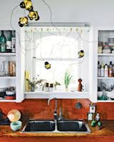 Kitchen, White Cabinet, and Wood Counter Above the sink in the kitchen, you can see one of Bocci’s first 57 chandeliers. Photo by José Mandojana.  Search “orbit two brass pendant light” from Light Fixtures We Love 