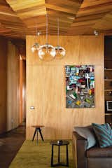 Michael O’Sullivan’s blown-glass pendant lights make another appearance in the living area, where a kauri-plywood wall showcases a piece by artist Martin Poppelwell. Photo by Emily Andrews.