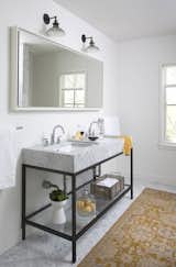 White walls, a luxurious marble double-sink, and an area rug give this bathroom an inviting atmosphere. "The natural light, open spaces, and light color palette make it a great place to wake up in the morning," Flournoy says of his home. The sink is from Restoration Hardware and the rug is from West Elm.