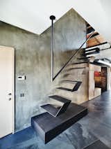 Futuristic floating stairs lead to the loft’s mezzanine. Throughout the lower level, natural stone was chosen for the flooring, laid at an irregular angle to add visual interest.
