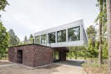 The lower level of this dramatically cantilevered house is covered in traditional red brick, while the upper level consists of coil-coated aluminium sheet with large glass panes.