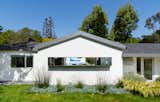 The architect kept the existing roof of this ranch-style house, streamlining it with Kynar-painted metal. The rest of the house is composed of white stucco.