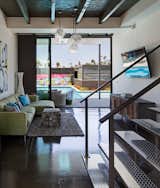 Loft-like features are used throughout the first floor interior space, including raw polished concrete floors, exposed beams (one of the few elements of the existing home that were preserved), and diamond-plate steel cladding on the floating staircase.  Photo 7 of 10 in A Dull Stucco Home Becomes a Modern California Oasis