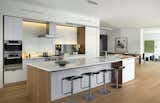 Kitchen, Engineered Quartz Counter, Refrigerator, Wall Oven, Cooktops, Range Hood, Range, Pendant Lighting, Light Hardwood Floor, and White Cabinet This kitchen features a sleek Henrybuilt kitchen system in white.  Photo 3 of 7 in A Modern Green Home in a Historic Colonial Town