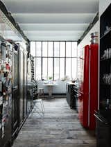 A Smeg refrigerator is one of a series of red accents that punctuate this black-and-white space.