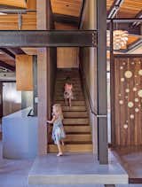 Staircase, Metal Railing, and Wood Tread The entrance is highlighted by a custom walnut door designed by the architect, Jack Hawkins. Cheryl Chenault designed the interiors.  Photo 2 of 19 in A Forest Sanctuary Designed to Support Autistic Triplets, Their Parents, and a Host of Caregivers