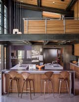 Norman Cherner barstools from Design Within Reach line the island in the kitchen, which is crowned by an open loft office. The faucets are from Dornbracht; the countertops are Caesarstone. Hawkins integrated a steel-clad casual eating nook, at left.