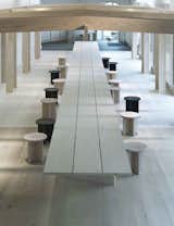 Custom stools can be pulled out to create a dining space. A wood pergola surrounds the table.