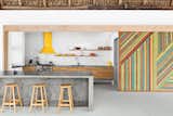 This rustic eucalyptus-log-and-thatch roof, located within an eclectic El Salvador beach house, counterbalances the effect of the monolithic concrete island and glossy subway tile backsplash.  Photo 4 of 4 in Backsplash by John Boudreau from Material-Rich Kitchens