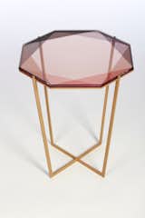 The Gem Glass Top Side Table is inspired by the reflections of light and transparencies found in gemstones. Depending on how the table is viewed, the color can change, just like the gemstones from which the table is iimagined. Each tabletop has a modular geometry that lends a sculptural quality to the table, while the bronze or zinc bases give a lofted, airy sensibility.