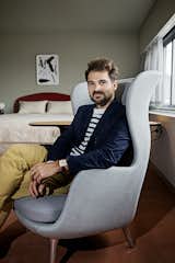 Hayon sits in the Ro armchair he designed for Fritz Hansen, one of the items he placed into the room. "As an artist and a furniture designer, I focus on the small elements rather than the big space," he says. "If you're comfortable on your chair, and it feels good, that's a really good starting point to have a successful space. Then I focus on the rest of the room in terms of color, ambiance, and lighting."  Photo 2 of 10 in Jaime Hayon Reimagines a Room in an Iconic Copenhagen Hotel