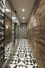 Black and white tiles add dramatic flair to the hallway that leads to the restrooms. The textural wood paneling found in the bar area wraps around one wall for continuity.