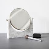 From design studio Studiopepe, this marble mirror is a sophisticated tabletop mirror that is crafted from marble, brass, and mirror glass. The marble is substantial and is designed to stand up on a tabletop, counter, or desk. The mirror is designed to tilt up and down, and features one magnifying side.