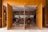 The library’s entrance features massive panel doors made of tropical freijó wood. Inside, leather armchairs by Jorge Zalszupin accent the space.