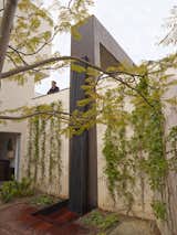 The two story outdoor shower and spa features a water wall formed of bent steel. If the homewowner prefers an extended dip, the lid of the hot tub can slide right up to the edge of the shower.